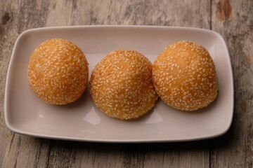 onde-onde or sesame balls are sweet snacks filled with green beans. sesame balls on a white ceramic plate.
