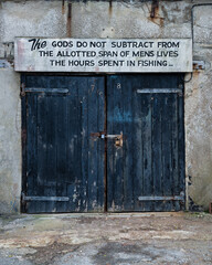 Image of old and weathered doors to fishing industry building in docks of Dorset with sea saying quote
