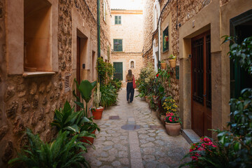 A serene moment in the flower-lined alleys of Fornalutx, Mallorca, where cobblestone paths and warm stone walls invite travelers to explore.