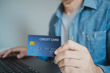 Close up, Man holding credit card while using laptop, shopping online, buying on internet. e-commerce e-banking service.