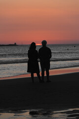 pareja de se&ntilde;ores de mediana edad viendo atardecer en la playa