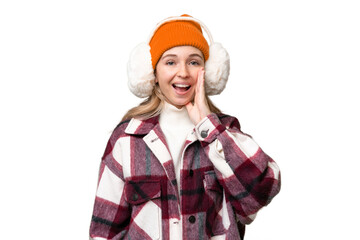Young  English woman wearing winter muffs over isolated background shouting with mouth wide open