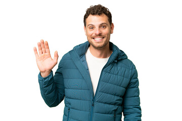 Fototapeta premium Brazilian man over isolated chroma key background saluting with hand with happy expression
