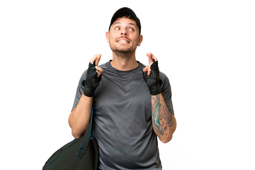 Young sport man with sport bag over isolated chroma key background with fingers crossing