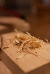 A pile of wood shavings rests on a wooden plank