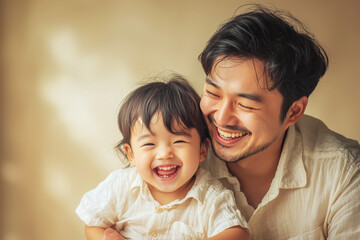 Parent and child share a joyful moment of laughter together in a close embrace against a soft beige background
