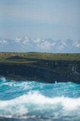 Montañas nevadas con pradera y olas