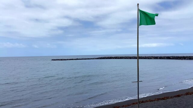 Green flag in the beach against blue sky and ocean water for safe swimming,4K video 