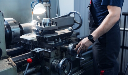 Male technician operating industrial lathe machine in factory setting