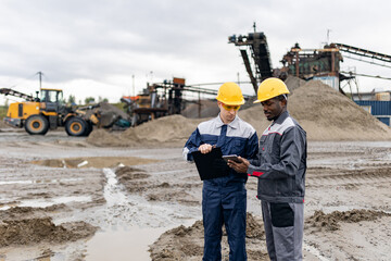 Portrait workers Caucasian and african mans engineers surveying sand quarry in ore mining site