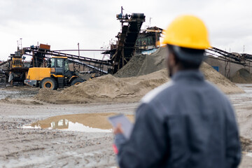 Male african adult engineer inspecting sand quarry mining operations