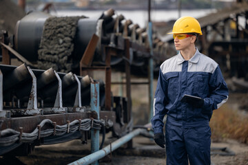 Caucasian man engineer in sand quarry ore mining site use tablet computer, controls transport...
