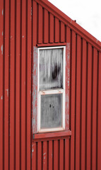 Ventana blanca congelada en pared de chapa roja