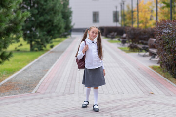 Caucasian girl in uniform and with a backpack goes from school. 