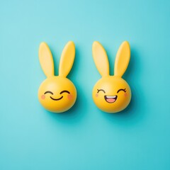Obraz premium Two cute happy yellow Easter emojis with bunny ears on pastel turquoise background and copy space.