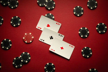 Several playing cards with a combination of three of a kind or set lie on a red table, surrounded...
