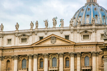 A large building St. Peter's Church of Vatican in Italy with a blue dome and a cross on top. The...