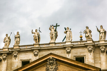 Obraz premium A large building St. Peter's Church of Vatican in Italy with a blue dome and a cross on top. The building has a lot of statues on it