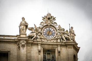 A large building St. Peter's Church of Vatican in Italy with a blue dome and a cross on top. The building has a lot of statues on it