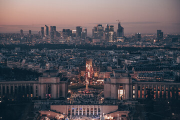 A Paris city with a large building in the center. The building is lit up at night. There are many cars on the street