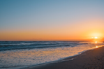 Fototapeta premium Warm hues of the setting sun illuminate the tranquil ocean.