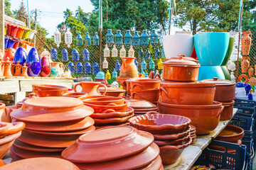 Close-up view of stacked terracotta cookware with a glossy finish displayed at an outdoor market.