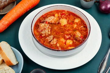 Bowl of red borscht with meat.