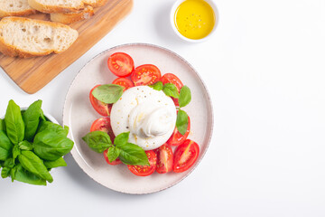 Delicious Italian caprese salad with sliced mozzarella, tomatoes, basil, and bread on background. 