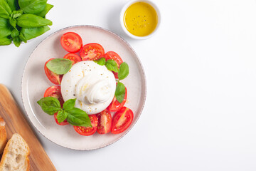 Delicious Italian caprese salad with sliced mozzarella, tomatoes, basil, and bread on background. 
