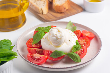 Delicious Italian caprese salad with sliced mozzarella, tomatoes, basil, and bread on background. 