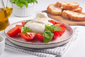 Delicious Italian caprese salad with sliced mozzarella, tomatoes, basil, and bread on background. 