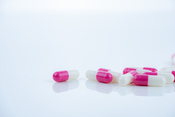 Pink-white antibiotic capsules spread on white background. Prescription drug. Antibiotic resistance in modern medicine. Healthcare and pharmaceutical industry. Medical care, pharmaceutical research.