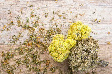 Dried bouquets of immortal flowers and yarrow flowers on wooden background, herbal medicine. Top...