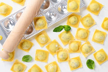Raw Homemade Ravioli pasta with spinach and ricotta cheese filling  on white background, top view