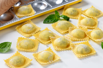 Raw Homemade Ravioli pasta with spinach and ricotta cheese filling  on white background