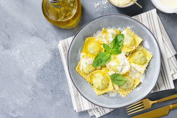 Homemade Ravioli pasta with spinach and ricotta cheese filling with creamy white sauce and grated Parmesan cheese. top view	