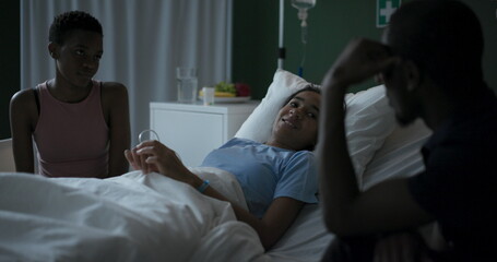 Fototapeta premium African child is seriously ill in a hospital room with her parents by her side, talking.
