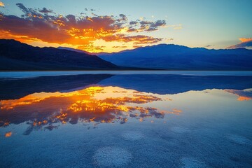 Sunset over a tranquil salt flat reflecting vibrant colors and distant mountains in a serene landscape