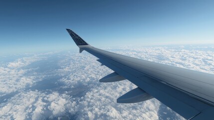 Obraz premium Airplane Wing Above Clouds with Clear Blue Sky Overlooking Beautiful Aerial Landscape During Flight