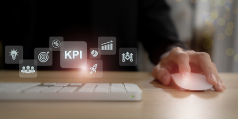 KPI and business analytics concept. Using a computer mouse with floating digital icons representing KPI, analytics, business performance metrics. Data-driven strategy and corporate efficiency.