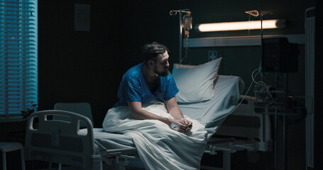 Beard male patient in hospital ward on bed.