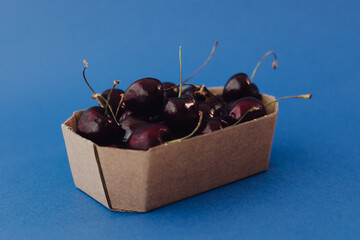 Fresh cherry in cardboard packaging on background. Healthy raw food, dessert without sugar and...