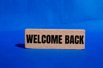 Welcome back message written on wooden block with blue background. Conceptual welcome back symbol....