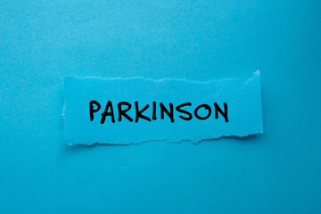 Parkinson message written on ripped torn paper piece on blue background. Conceptual parkinson symbol. Copy space.