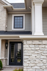 Modern House Exterior: Grey Siding, Black Windows, and Stone Accents