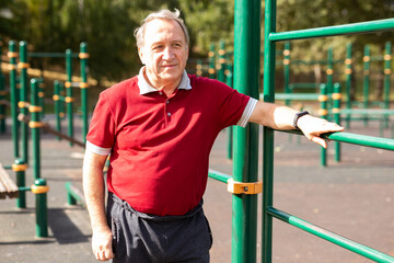 Elderly man stands in a sports bar on an outdoor sports field