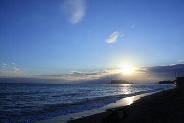 鎌倉・七里ヶ浜海岸から見る江ノ島とオレンジ色になる夕陽とのある風景　夕景