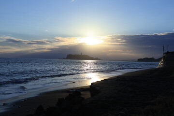 鎌倉・七里ヶ浜海岸から見る江ノ島とオレンジ色になる夕陽とのある風景　夕景