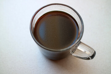 A glass of black coffee in a transparent glass, photographed from the top