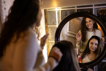 two women talking in front of a mirror
